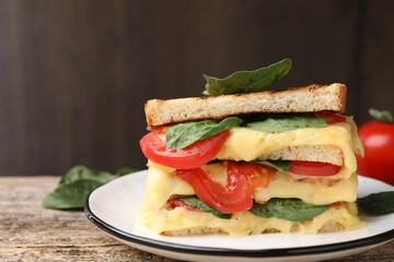 Delicious sandwiches with melted cheese, spinach and tomatoes on wooden table, closeup