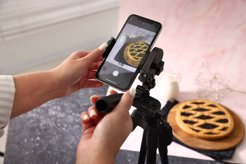 Woman taking picture of tasty pie and milk in studio, selective focus. Professional food photography