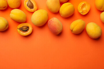 Many fresh apricots on orange background, flat lay. Space for text