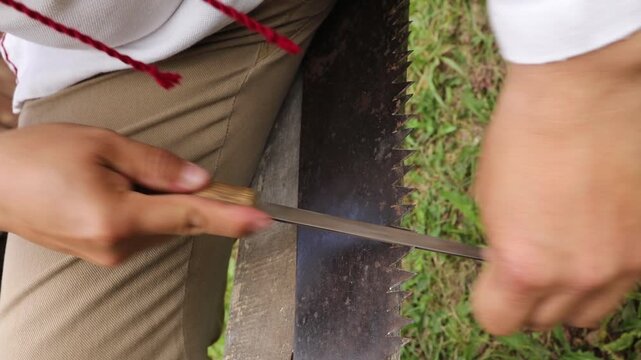 Sharpening a Tool on Grass with Great Precision, Attention, and Care in a Natural Setting