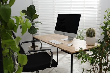 Biophilic interior design. Stylish workplace with computer and houseplants in office