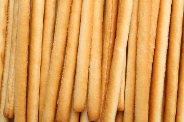 Delicious grissini sticks as background, top view