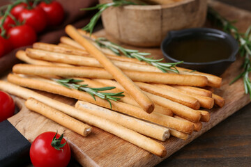 Delicious grissini sticks served on wooden table, closeup