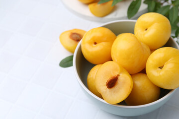 Ripe yellow cherry plums on white tiled table, closeup. Space for text