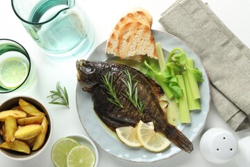 Tasty roasted flounder fish with celery served on white table, flat lay. Homemade seafood dish