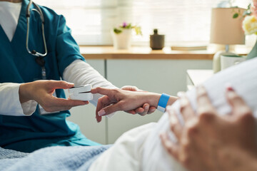 Caucasian young adult woman lying in hospital bed receiving care from medical professional, nurse...