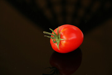 Fresh tomatoes on a black mirror background.