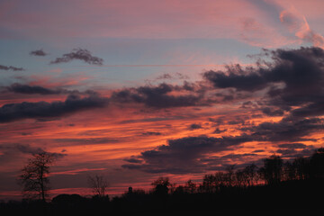 bellissimo e particolare tramonto dalle sfumature brillanti di colore arancione, visto da un ambiente naturale e rurale delle campagne del nord Italia, in inverno