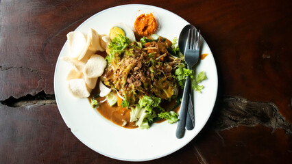 Indonesian specialty food, namely gado-gado, which is served on a white plate on a wooden table