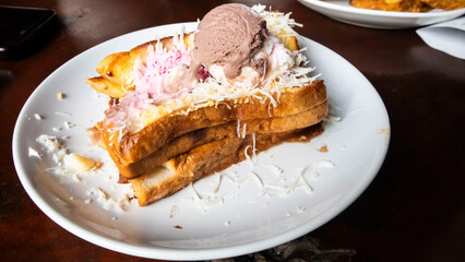 toast, ice cream and cheese flakes on a white plate on the table