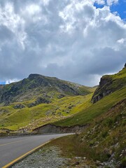 Beautiful alpine view on the side of the Transalpina Road in Parang Mountains with cliffs, green grass and sheep grazing in the background on a summer day. Valcea, Romania