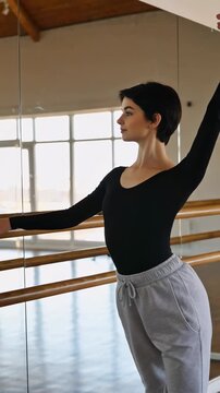 Ballet dancer practices at the studio during a sunny afternoon in a spacious mirror-lit space