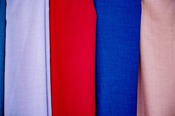 Background made of white, red, blue, and pink fabric rolls, concept of tailoring, sewing, clothing repair, fashion, and design.