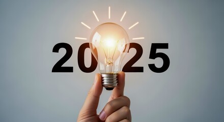 Year 2025 Creative Concept: Hand Holding Illuminated Lightbulb Symbolizing Innovation, Future Technology, and Vision