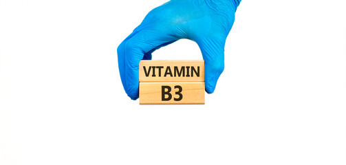 Vitamin B3 niacin symbol. Concept words Vitamin B3 on beautiful wooden blocks. Doctor's hand in blue medical glove. Beautiful white background. Medical healthy lifestyle Vitamin B3 niacin concept.