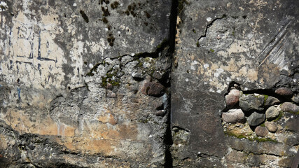 Exploring the textures and history of an aged stone wall in a forgotten location under bright sunlight