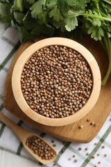 Coriander seeds and fresh cilantro on white table, top view