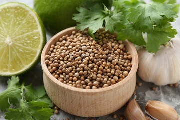 Coriander seeds, fresh cilantro, lime and garlic on grey textured table, closeup
