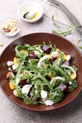 Tasty salad with arugula, cheese, peach, beetroot and nuts on grey table, above view