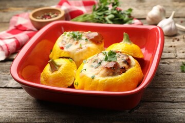 Tasty stuffed pattypan squashes in baking dish on wooden table, closeup
