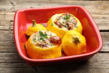 Tasty stuffed pattypan squashes in baking dish on wooden table, closeup