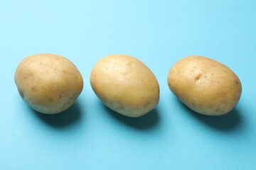 Fresh raw potatoes on light blue background