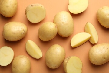 Fresh raw potatoes on light brown background, flat lay