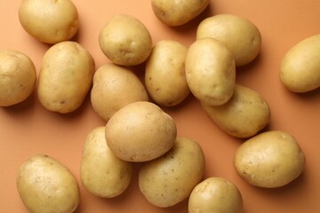 Fresh raw potatoes on light brown background, above view