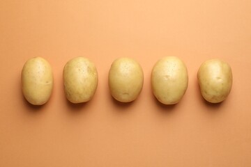 Fresh raw potatoes on light brown background, top view