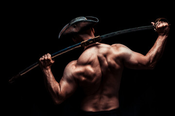 Shirtless pirate figure holding sword over shoulder in dark studio