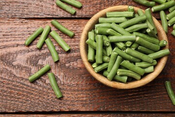 Pieces of fresh pea pods and bowl on wooden table, flat lay