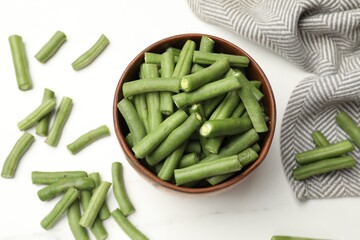 Pieces of fresh pea pods, bowl and napkin on white table, flat lay