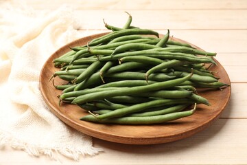 Fresh pea pods and napkin on light wooden table, closeup