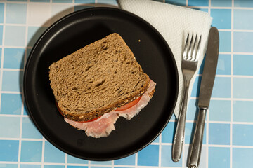 Classic ham and tomato sandwich on multigrain bread with a glass of juice