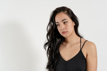 Naklejka premium Young latin woman feeling sad and looking down on white background