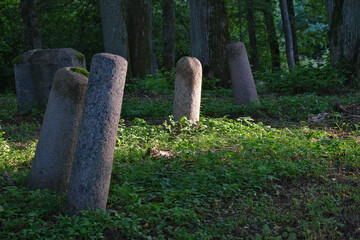 old hand carved granite fence columns in old Latvia forest cemetery.