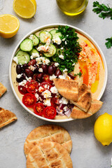 Greek style hummus bowl with vegetables, olives, feta and pita. top view .