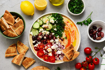 Greek style hummus bowl with vegetables, olives, feta and pita. top view .