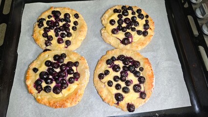 Freshly baked pastries with cottage cheese filling and blueberries on parchment paper. Concept of homemade baking, traditional dessert and comfort food