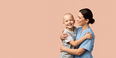 Female nurse embracing a happy bald child patient. Smiling boy after chemotherapy with a healthcare worker. Pediatric care concept with copy space.