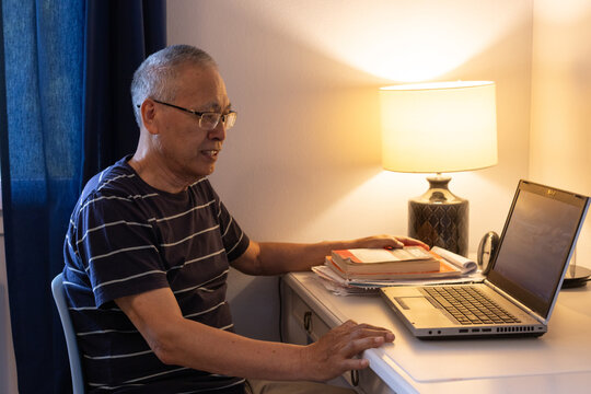 asian senior man using laptop computer at home, watch webinar or video