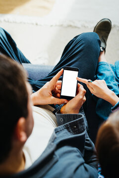 father and daughter interacting with smartphone while relaxing on sofa