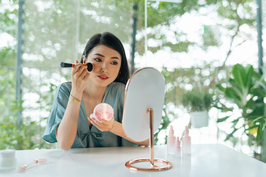 Model having blush applied to cheekbones during makeup session