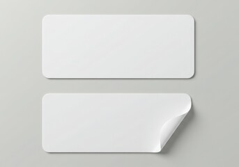 Two blank white rectangular stickers isolated on white background, one slightly peeled