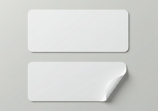 Two blank white rectangular stickers isolated on white background, one slightly peeled