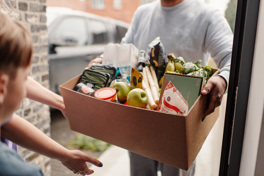 Hand accepting grocery delivery at front door
