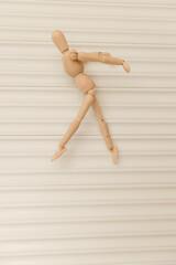 Wooden mannequin figure depicting a ballet dancer movement on a white background.