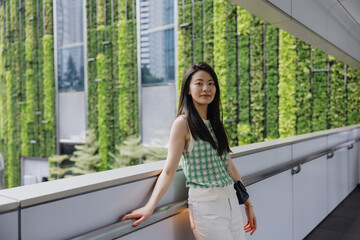 Woman standing on walkway in front of green vertical garden wall