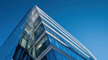 The modern glass building with striking angles against a clear blue sky