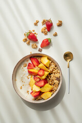 Granola or muesli with natural greek yogurt, strawberry and peach in a bowl and scattered on a white background